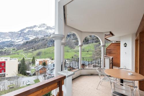 a balcony with a table and chairs and mountains at Residenz Ambassador in Leukerbad