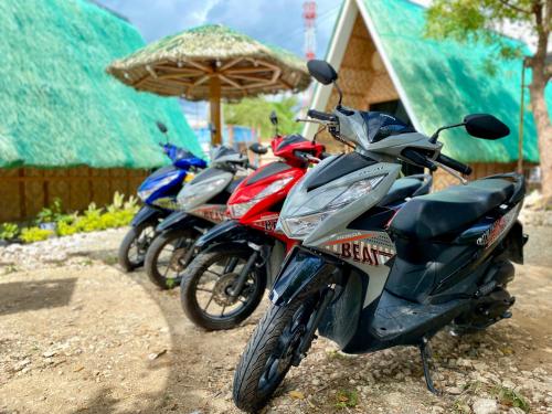 three motorcycles parked next to a building with an umbrella at Moalboal Panagsama beach TopBudz Hostel in Moalboal