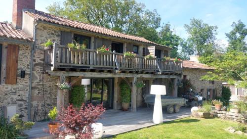 a house with a balcony with flowers on it at Gîte et Chambres d'Hôtes du Petit Moulin in Réaumur