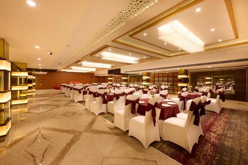 a large banquet hall with white tables and chairs at Delite Sarovar Portico Faridabad in Faridabad