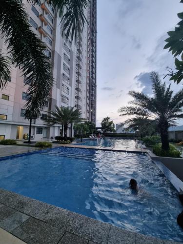a large swimming pool with palm trees and a building at Studio Condo Unit at Horizons 101 in Cebu City
