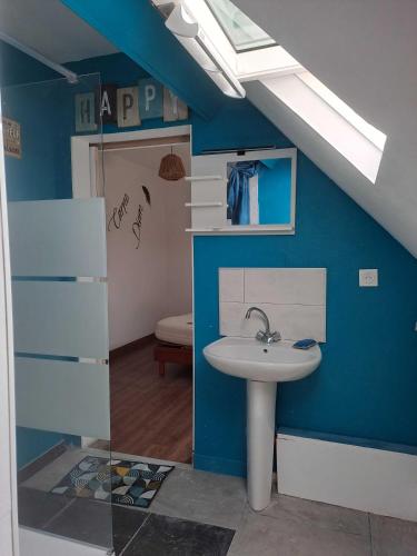 La salle de bains est pourvue d'un lavabo et d'un mur bleu. dans l'établissement La JUFE, à Cormeilles
