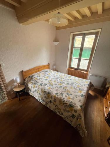 - une chambre avec un lit doté d'un couvre-lit floral et d'une fenêtre dans l'établissement Maison de campagne, à Anost