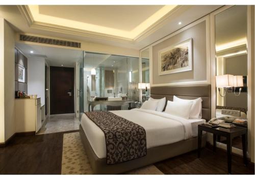 a bedroom with a large bed and a bathroom at Singhania Sarovar Portico in Raipur