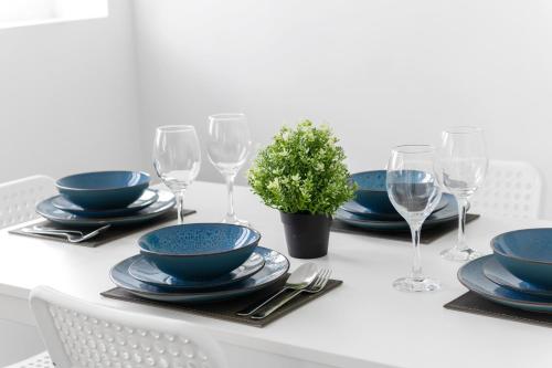 a table with blue bowls and plates and wine glasses at JASIG APARTMENTS - Comfy 3 Bedroom house in Nottingham, Sleeps 6 in Nottingham