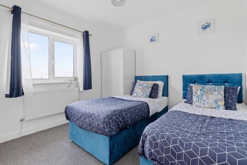 a bedroom with two beds and a window at JASIG APARTMENTS - Comfy 3 Bedroom house in Nottingham, Sleeps 6 in Nottingham