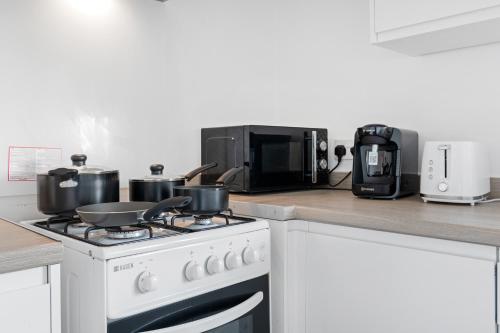 a kitchen with a stove with pots and pans on it at JASIG APARTMENTS - Comfy 3 Bedroom house in Nottingham, Sleeps 6 in Nottingham