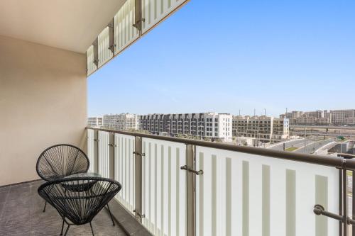 a balcony with a chair and a view of a city at Silkhaus Vacation Homes Modern 2BDR Near Banks of Al Rahah in Abu Dhabi