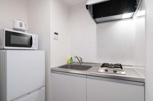a kitchen with a sink and a microwave and a refrigerator at KISETSU Omori II in Tokyo