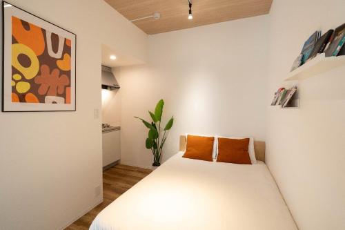 a bedroom with a white bed with orange pillows at KISETSU Omori II in Tokyo