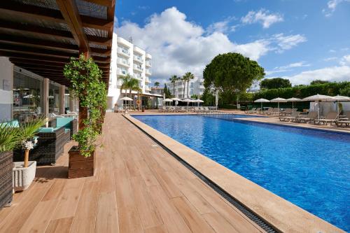a pool at a hotel with blue water at AluaSun Continental Park Hotel & Apartments in Playa de Muro