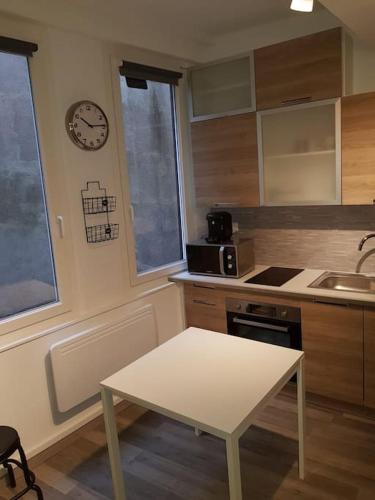 une cuisine avec une table et une horloge au mur dans l'établissement Le cocon, à Besançon