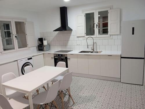 a white kitchen with a table and white appliances at Casa Mayor in Huérmeces