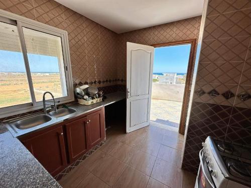 a kitchen with a sink and a counter with a window at LEBNA Plage in Nabeul