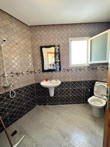 a bathroom with a sink and a toilet and a mirror at LEBNA Plage in Nabeul