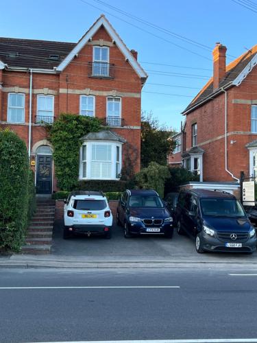 three cars parked in a parking lot in front of a house at The Glastonbury Townhouse B&B in Glastonbury
