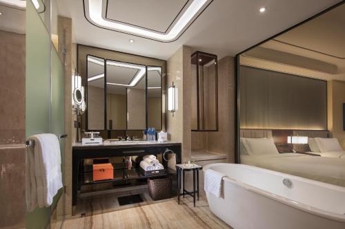 a bathroom with a bath tub and a bed at Hilton Fuzhou in Fuzhou
