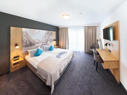 ein Hotelzimmer mit einem großen Bett und einem Schreibtisch in der Unterkunft Hotel Hanauerlehen - ruhige & zentrale Top-Lage - mit Schwimmbad, Sauna, Parkplätze & Café - bayerischer Familienbetrieb in Schönau am Königssee
