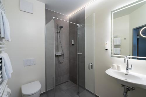 a bathroom with a shower and a toilet and a sink at City Hotel Stockerau in Stockerau