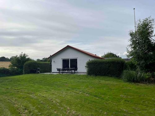 a white shed with a picnic table in a yard at Flot renoveret sommerhus, tæt på vandet in Frørup