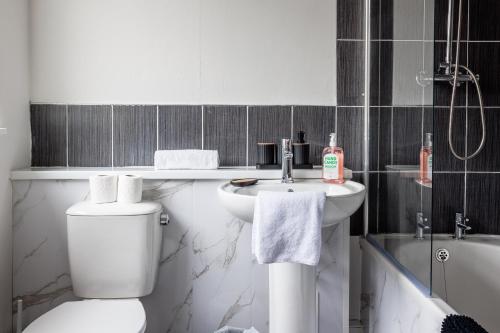 a white bathroom with a toilet and a sink at Enjoy a spacious 3 BR home in Sunderland