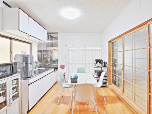 a kitchen with white cabinets and a table and chairs at ゲストハウス 畔（hotori） in Nishimukai