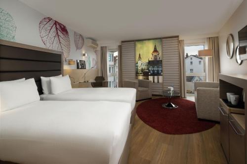 a bedroom with a large white bed and a living room at DoubleTree by Hilton Hannover Schweizerhof in Hannover