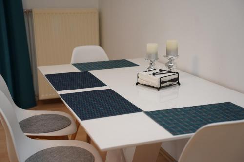 a white table with four chairs and two candles on it at Moderne Ferienwohnung in Schwandorf in Schwandorf in Bayern