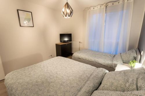 Cette chambre comprend deux lits, une télévision et un canapé. dans l'établissement T3-2 min metro-24 24h, à Toulouse