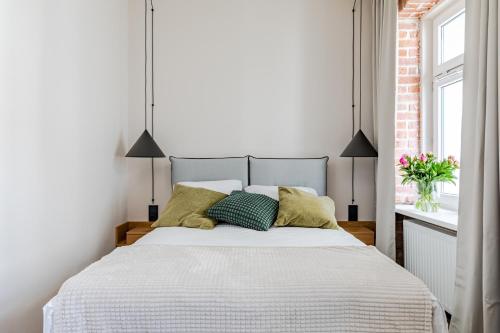 a white bedroom with a bed with green pillows at Mińska Apartament in Warsaw