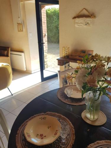 une table avec des assiettes et un vase avec des fleurs. dans l'établissement Pause campagne, à La Chapelle-Bouexic