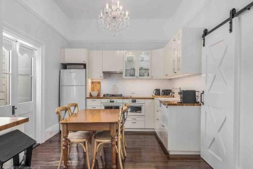 a kitchen with white cabinets and a wooden table and chairs at Warm, Inviting & Luxurious The Barn in Sandy Bay