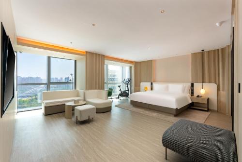 um quarto com uma cama e uma sala de estar com um sofá em EVEN Hotel Qingdao Laoshan - an IHG Hotel em Qingdao