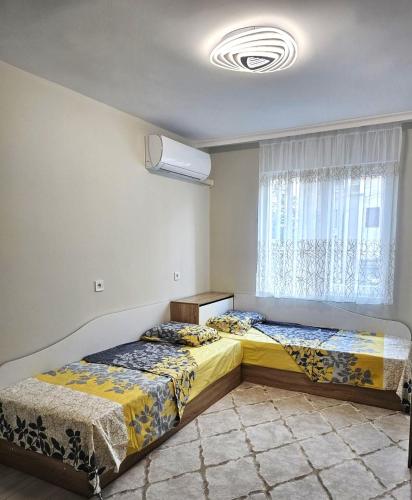 two beds in a room with a window at Apartment Bohemi with free parking in Burgas