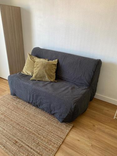 un canapé bleu avec deux oreillers sur le sol dans l'établissement Appartement 1 pièce, Hyper centre, Grosse Horloge, à La Rochelle