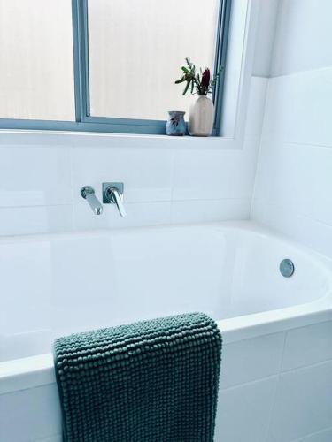 a bathroom with a sink and a chair under a mirror at Clarys House - Nestled in the heart of Tanunda in Tanunda