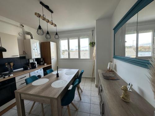 une cuisine avec une table en bois et des chaises bleues dans l'établissement Appartement vue Scorff Lanester, à Lanester