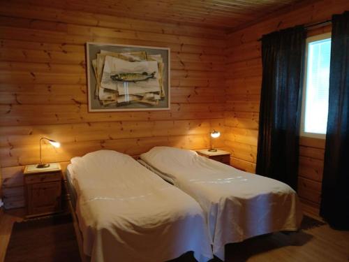 a bedroom with a bed and two lamps on two tables at Loghouse in Hjorto in Ödkarby