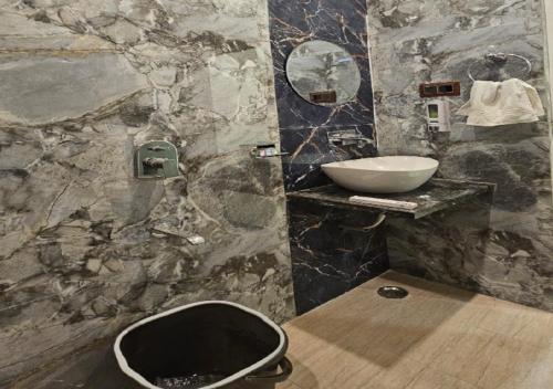 a stone bathroom with a sink and a mirror at Triveni International in Varanasi
