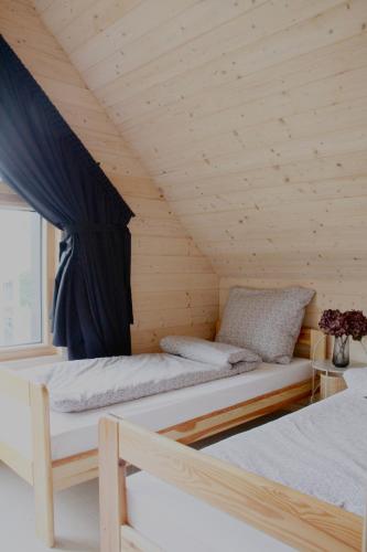 a room with two beds in a wooden cabin at Poczywaj in Jordanów