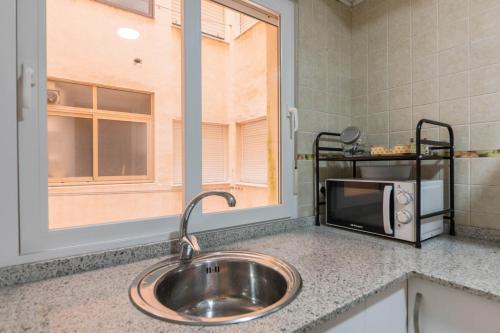 a kitchen counter with a sink and a microwave at Jardin del Mar Primera Linea Mediterráneo 3 dormitorios 2 baños in La Manga del Mar Menor