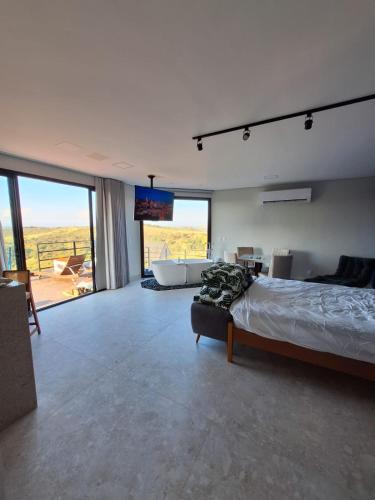 a bedroom with a bed and a tub and a television at Lux Lodge in Jaboticatubas