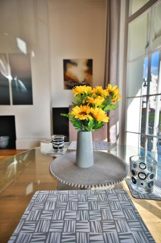 a vase with yellow flowers sitting on a table at 40b Wellington Suites in Hastings