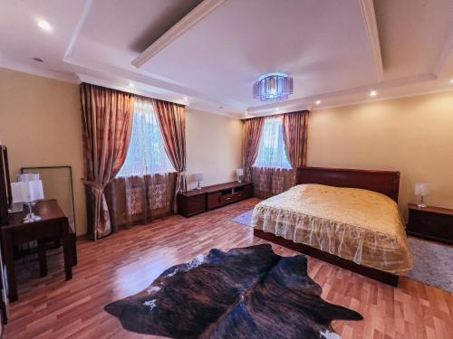 a bedroom with a bed and two windows at Kolsay Tanbalytas Villa in Kolʼbastau