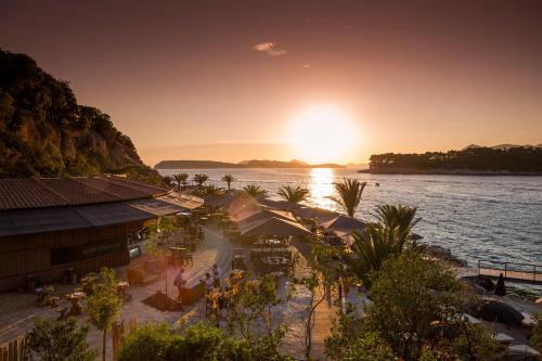 a view of a beach with the sun setting over the water at Valamar Argosy Hotel in Dubrovnik
