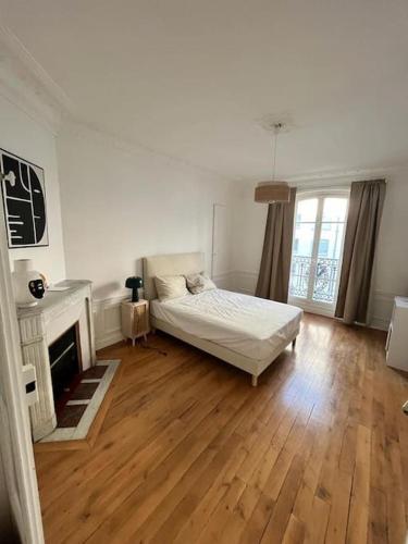 une chambre blanche avec un lit et une cheminée dans l'établissement Bel appartement à Paris, à Paris