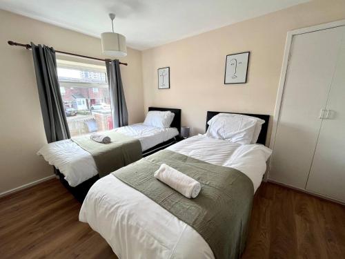 ein Schlafzimmer mit zwei Betten und einem Fenster in der Unterkunft Central 4 Bedroom House With Driveway in Newcastle upon Tyne