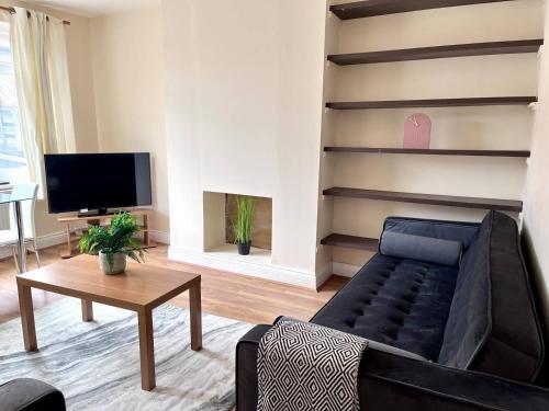 ein Wohnzimmer mit einer schwarzen Couch und einem Fernseher in der Unterkunft Central 4 Bedroom House With Driveway in Newcastle upon Tyne