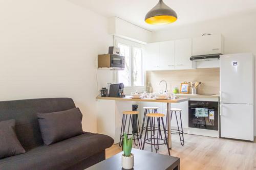un salon avec un canapé et une cuisine dans l'établissement ZenBNB - Kanji - Proche Tram - Parking Privé -, à Ambilly