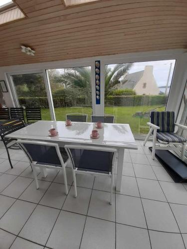une table blanche et des chaises sur une terrasse dans l'établissement Parc an aod, à Plougonvelin